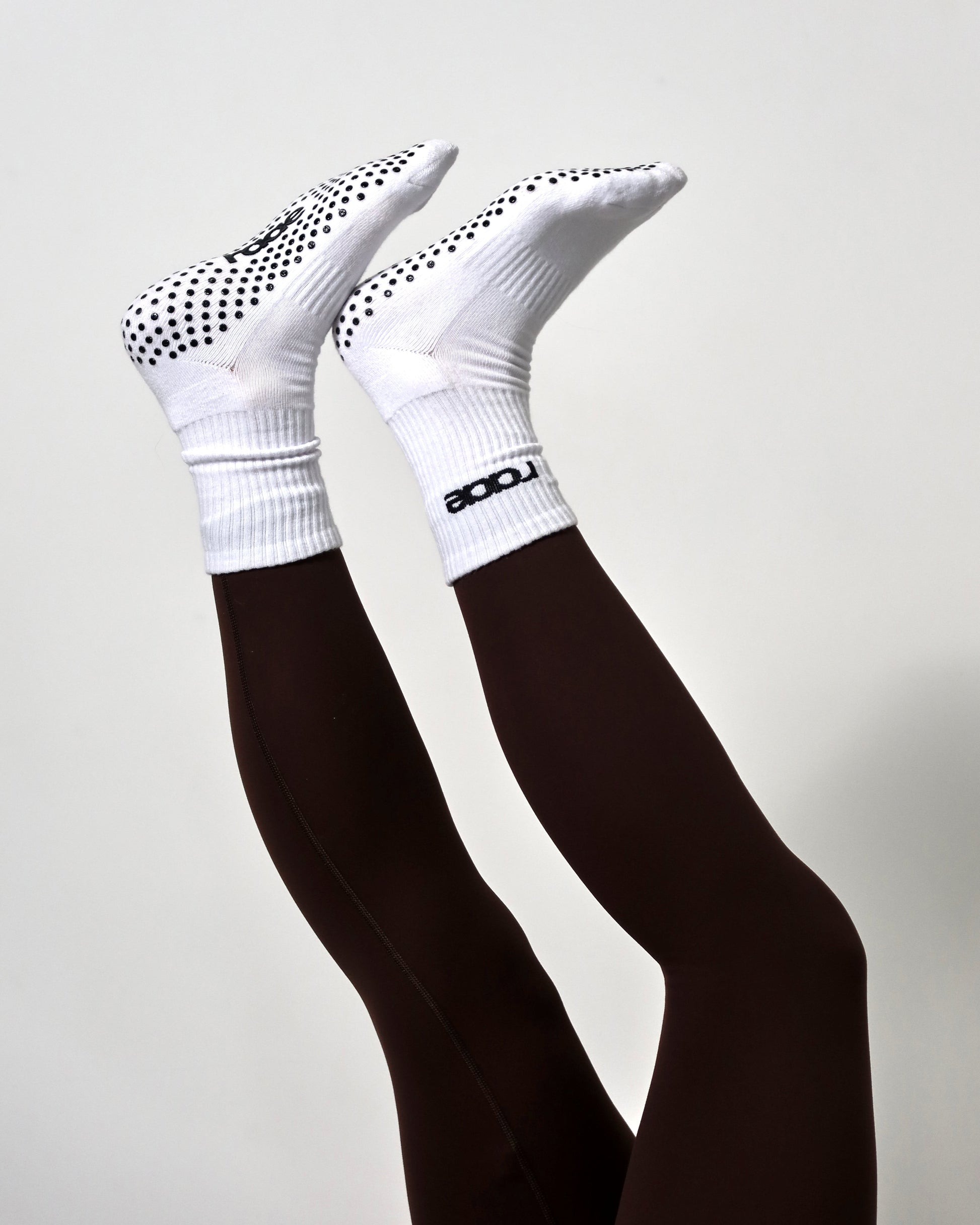 White socks with black dots and 'raae' branding on a white background activewear raae uk
