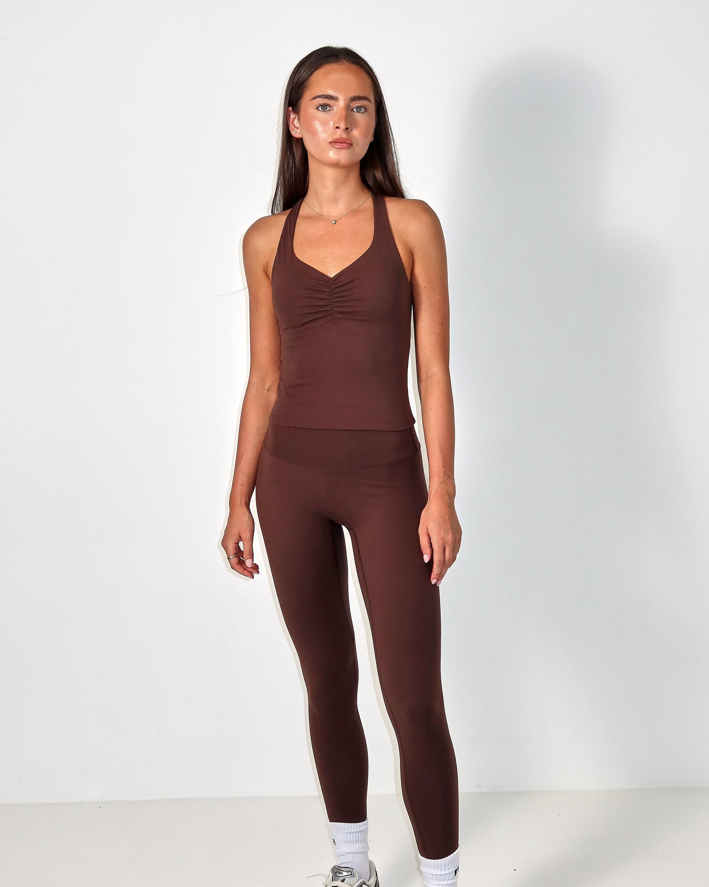 Woman wearing a brown activewear outfit on a white background activewear raae uk