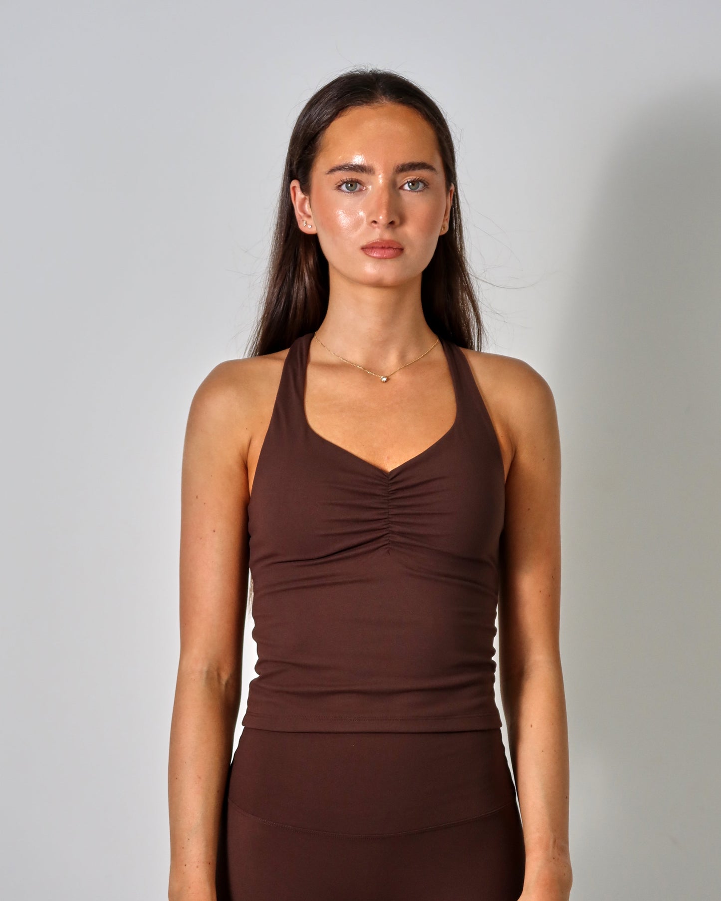 Woman wearing a brown tank top and leggings against a plain background activewear raae uk