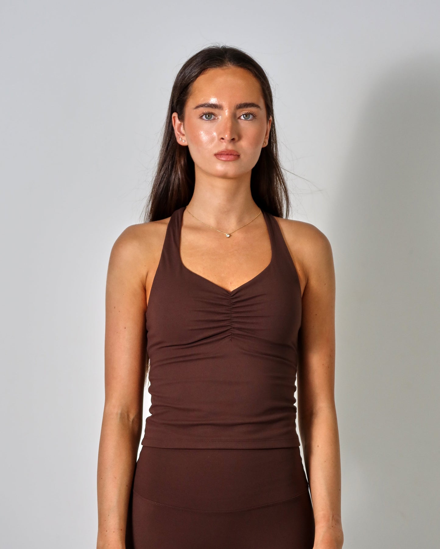 Woman wearing a brown tank top and leggings against a plain background activewear raae uk