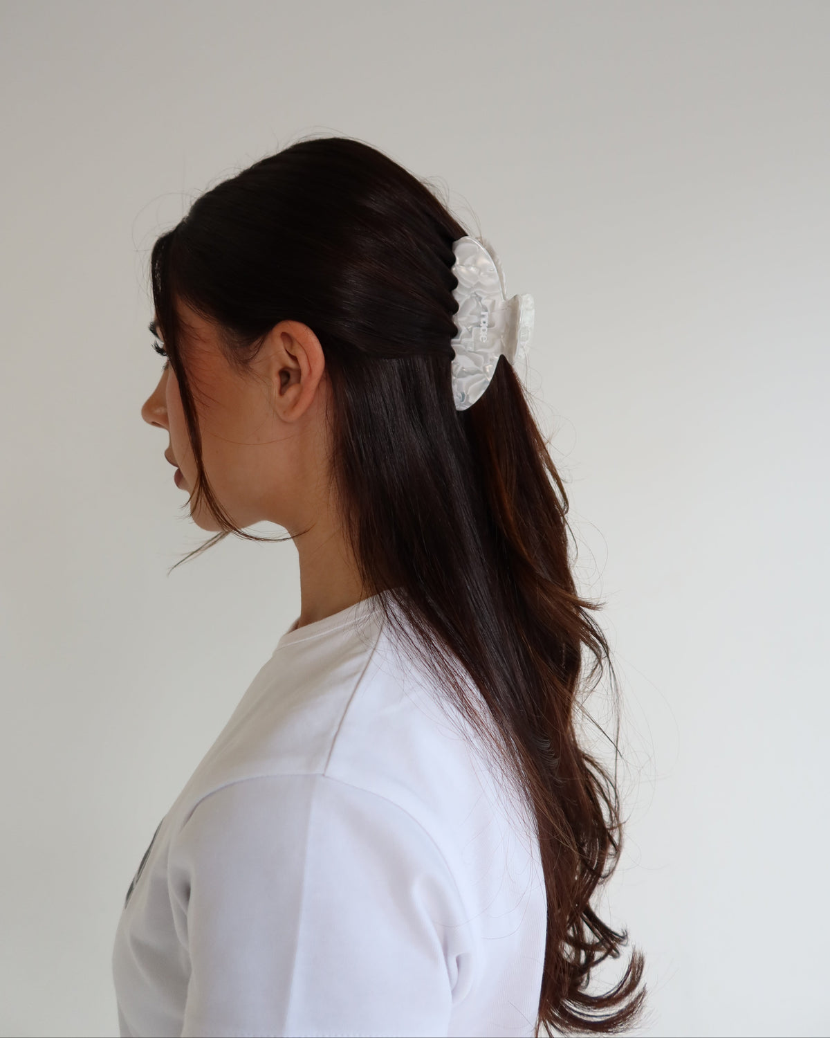 Person with hair tied back using raae white claw clip