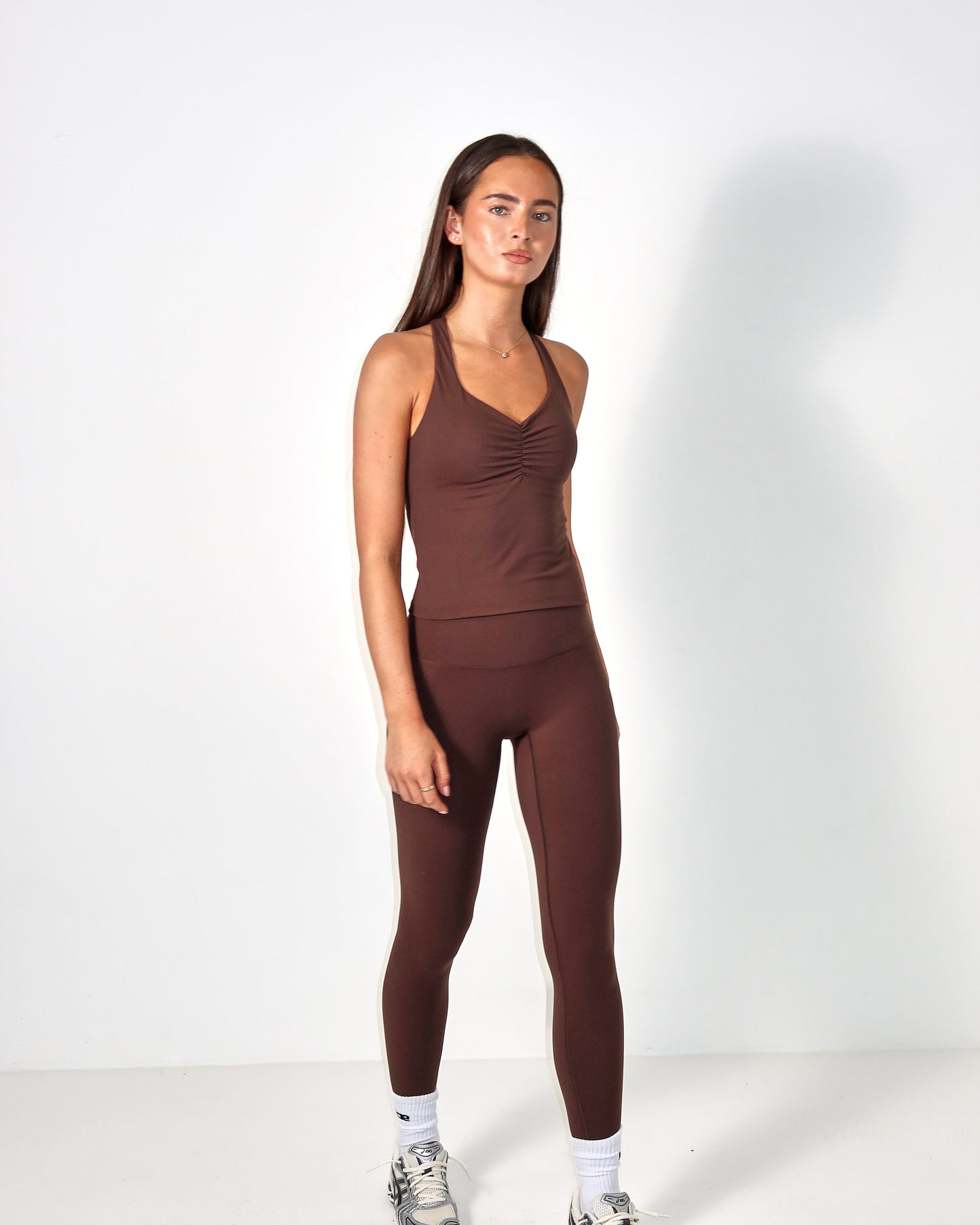 Woman wearing a brown tank top and leggings set on a white background activewear raae uk