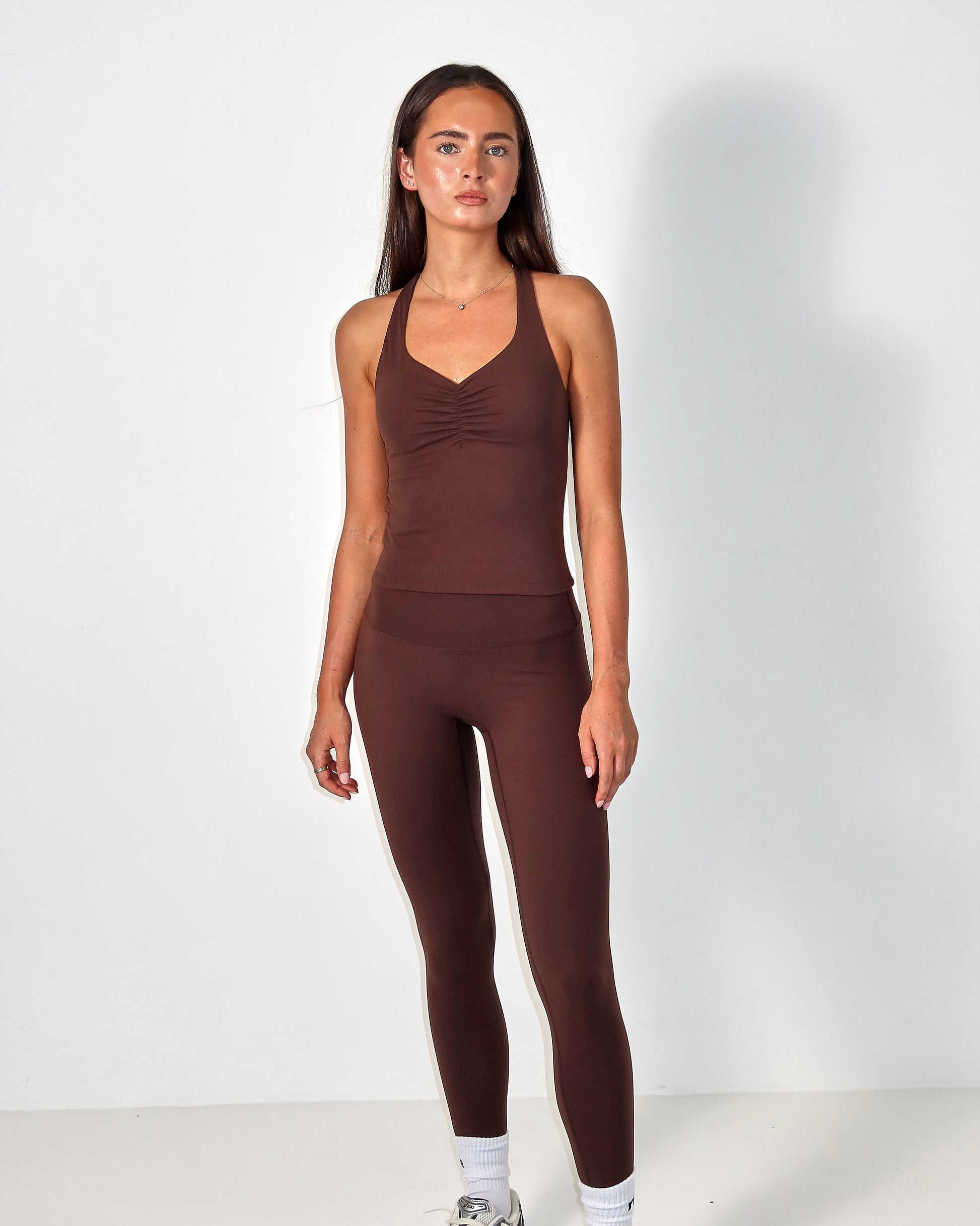 Woman wearing a brown activewear outfit on a white background activewear raae uk