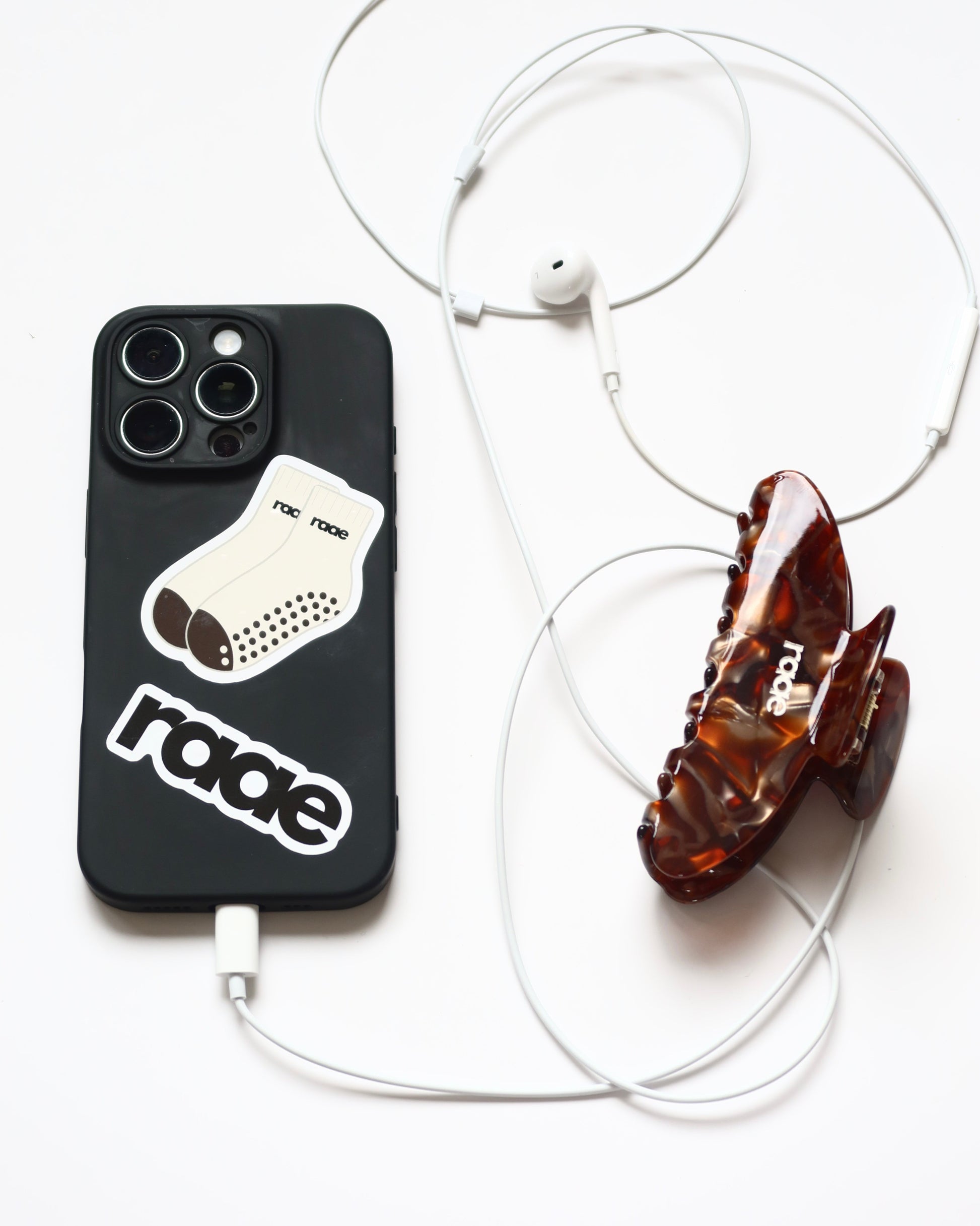 Phone case with a sock design, sunglasses, and earphones on a white background activewear raae uk